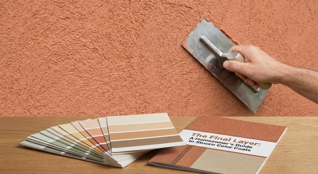 Close-up of a residential home exterior featuring a freshly applied stucco color coat with a sand finish texture.